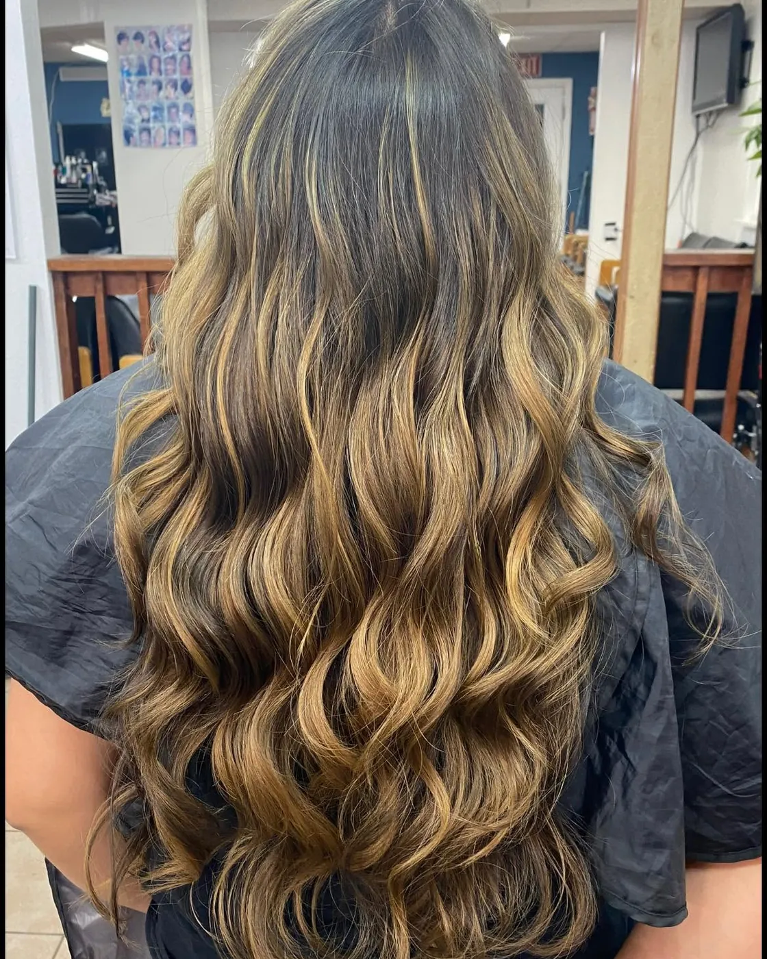 Long caramel balayage curls, seen from behind in the salon chair